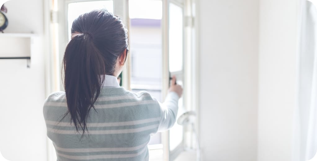 窓を開けて換気する女性の写真